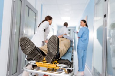 Doctors transporting patient on gurney to operating room clipart