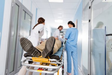 Doctors in uniform transporting patient to operating room clipart