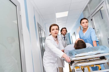Endişeli doktor ve hemşire sedye üzerinde bilinçsiz hasta taşıma