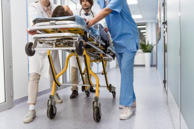 Cropped view of doctors and nurse transporting unconscious patient clipart