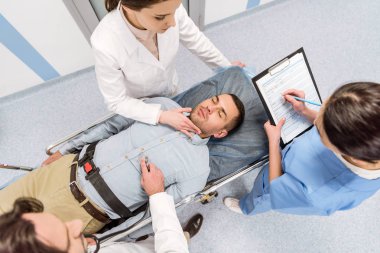 Top view of doctors transporting unconscious patient and checking pulse clipart