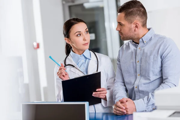 Brunette Médecin Avec Presse Papiers Parler Patient Clinique — Photo