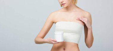 cropped view of girl in breast bandage after plastic surgery holding plastic container with medicines, isolated on grey clipart