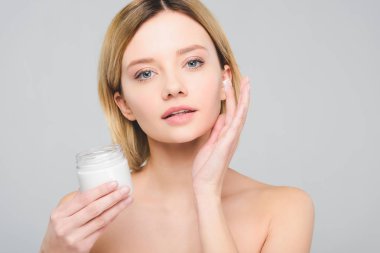 yüzünde kozmetik krem uygulamak ve plastik konteyner gri izole tutan çekici kız