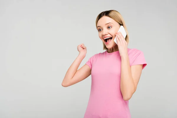 兴奋的美丽的女人在粉红色的 T恤上谈论智能手机 孤立在灰色 — 图库照片