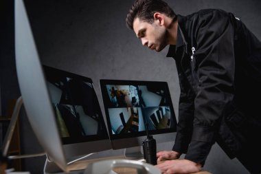 focused guard in uniform looking at computer monitor at workplace  clipart