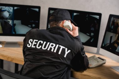 rear view of guard in uniform talking on telephone at workplace  clipart