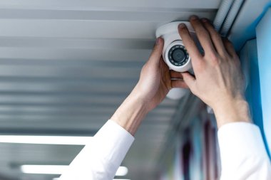 partial view of man setting up security camera clipart