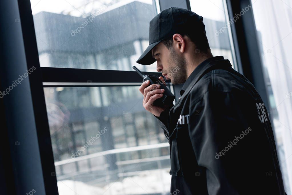 handsome guard in black uniform talking on walkie-talkie 