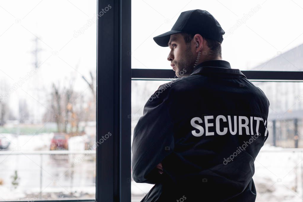 rear view of guard in black uniform with earphone 