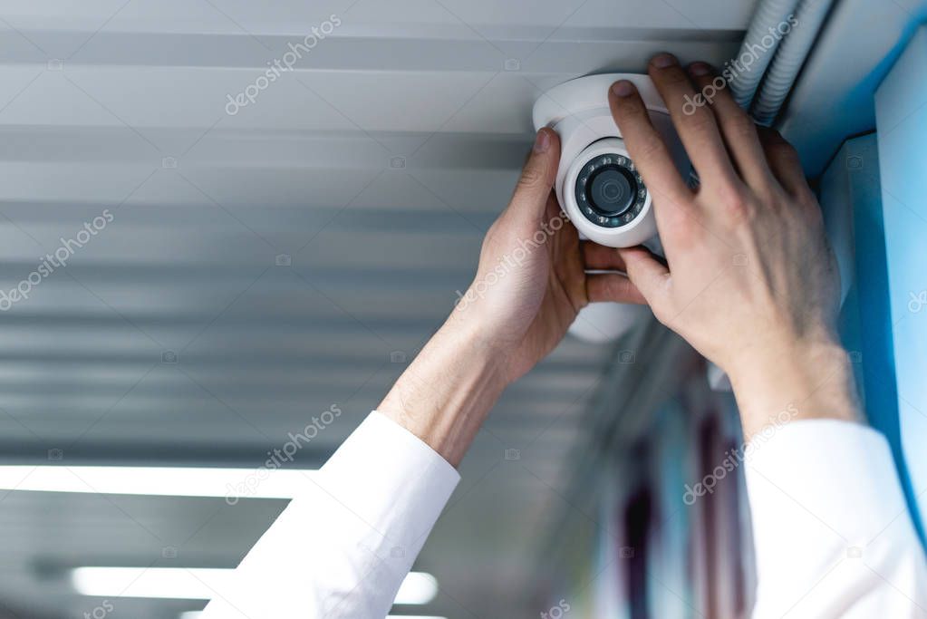 partial view of man setting up security camera
