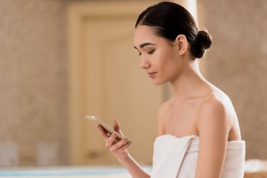 çekici kadın kopya alanı ile Spa'da smartphone kullanarak havlu
