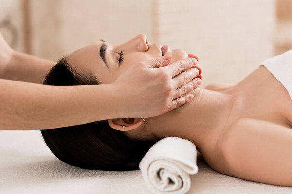  beautiful woman getting face massage with closed eyes at spa 