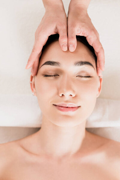 attractive woman getting face massage with closed eyes at spa 