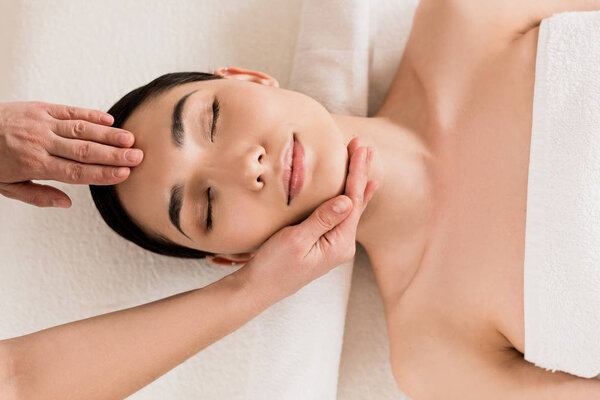 attractive woman getting face massage with closed eyes at spa 