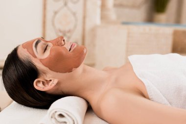 çekici kadın kil maskesi Spa'da yüzündeki yalan yan görünüm 