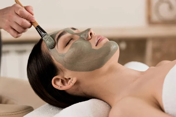 女性顔の粘土のマスクを適用する美容師のビューをトリミング — ストック写真