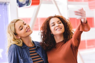 gülümseyen seçici odak ve çekici kadın selfie ile smartphone café'de alarak 