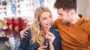 beautiful woman holding glass bottle with soda and hugging with handsome man  clipart
