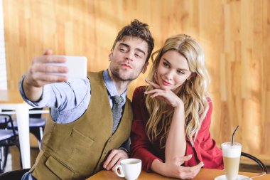 yakışıklı ve çekici kadın selfie café'de alarak seçici odak 