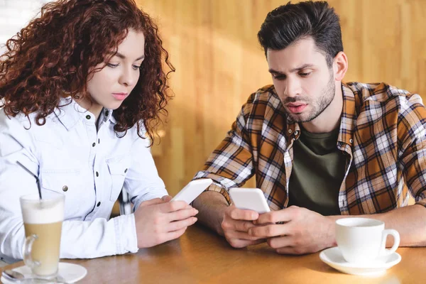 ハンサムな男性と美しい女性がカフェでスマート フォンを使用して — ストック写真