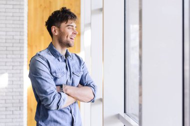 yakışıklı ve gülümseyen bir adam uzakta café'de seyir çapraz kollu 