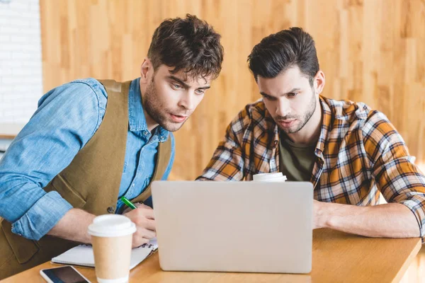 Amigos Bonitos Focados Usando Laptop Com Copo Papel Mesa Café — Fotografia de Stock