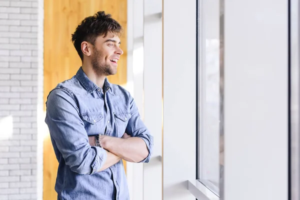 handsome and smiling man with crossed arms looking away at cafe