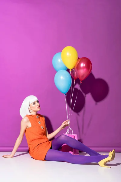 Jovem Elegante Peruca Segurando Balões Sentado Fundo Roxo — Fotografia de Stock