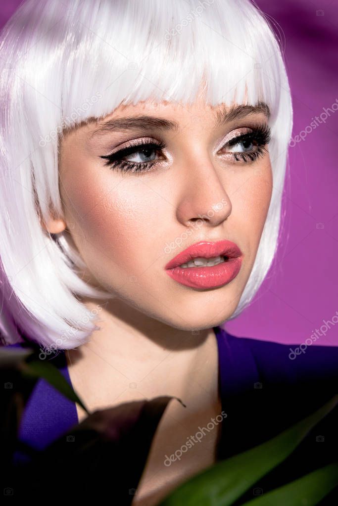 Sensual young woman in white wig looking away on purple background