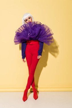 Kırmızı pantolon Sarı zemin üzerine çapraz ayaklı ayakta sıkılmış kız görünümünü tam uzunlukta