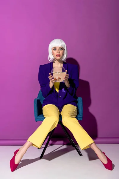 Amazed Woman Wig Sitting Armchair Holding Aquarium Goldfishes Purple Background — Stock Photo, Image