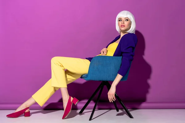 Charming Girl White Wig Sitting Armchair Looking Away Purple Background — Stock Photo, Image