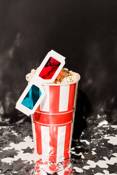 Cup with popcorn and 3d glasses on dark background