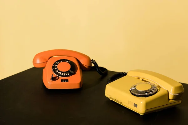 Dois Telefones Antigos Mesa Preta Fundo Amarelo — Fotografia de Stock