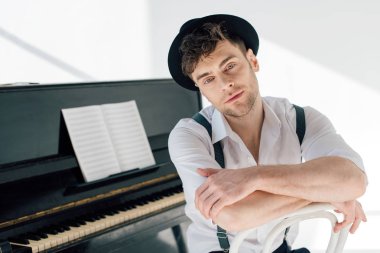 dreamy pianist in white shirt and black hat looking at camera clipart