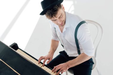 handsome musician in white shirt and black hat playing piano clipart