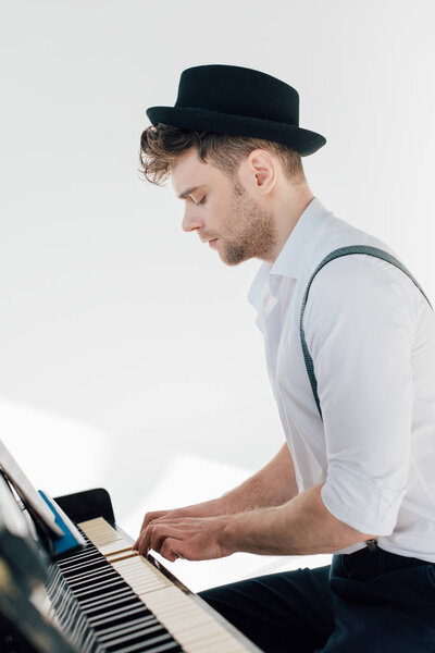 concentrated pianist in stylish clothing playing piano 