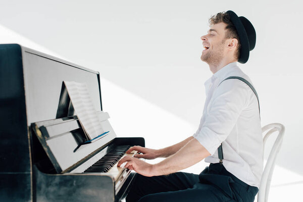 возбужденный пианист в стильной одежде играет на пианино
 