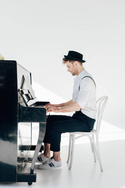 concentrated pianist in trendy clothing playing piano 