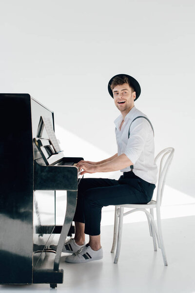 inspired pianist in white shirt and black hat playing piano 
