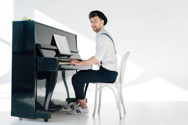 smiling pianist in trendy clothing playing piano 
