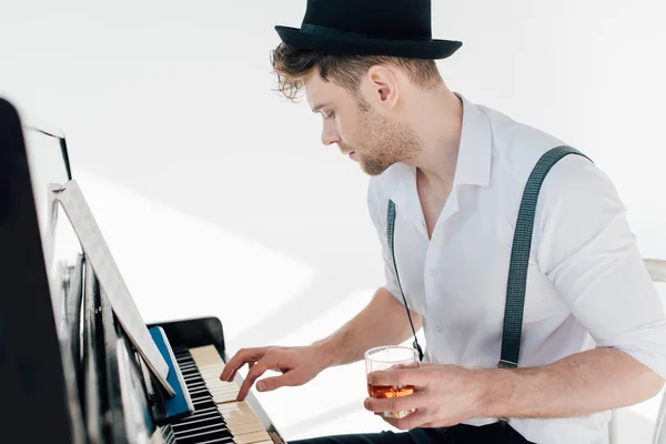 英俊的钢琴家拿着一杯酒精饮料 而弹钢琴 — 图库照片
