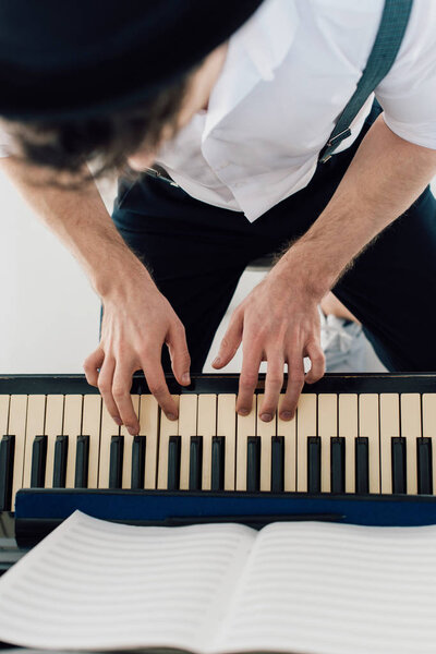 selective focus of pianist in white shirt playing piano 