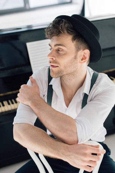 selective focus of dreamy composer in white shirt and black hat