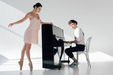 handsome pianist playing while beautiful ballerina dancing near piano  clipart