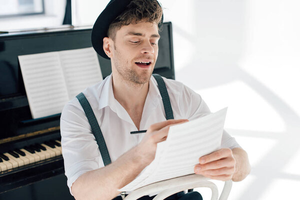 selective focus of cheerful man composing music at home