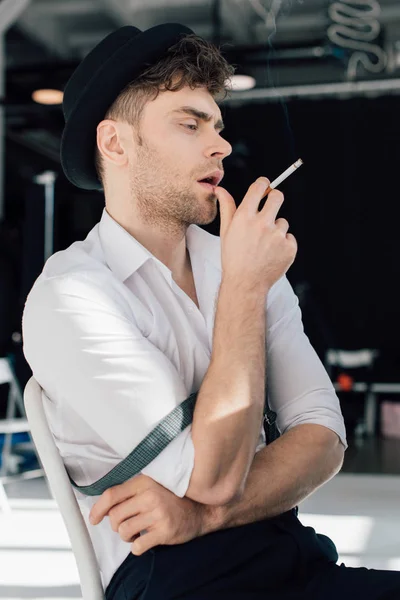 Drömmande Stilig Man Vit Skjorta Och Svart Hatt Rökning Cigarett — Stockfoto