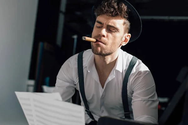 英俊的音乐家拿着音乐书页 同时抽雪茄 — 图库照片