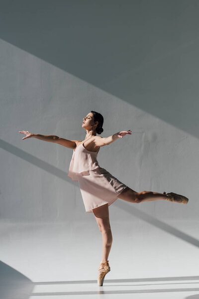 young ballerina  dancing in pink dress and pointe shoes